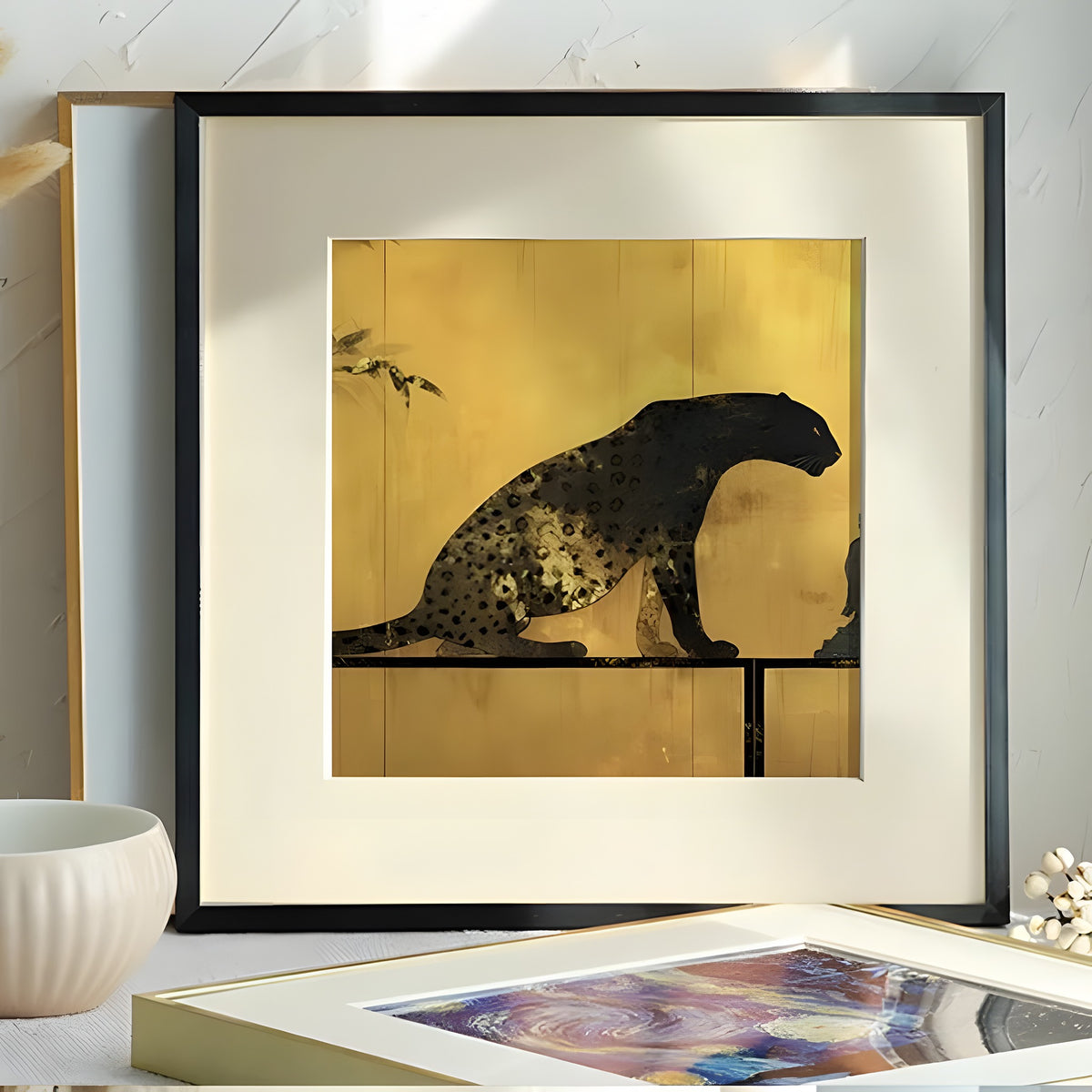 Framed artwork of a leopard on a gold background in a room setting.