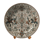 Decorative plate with intricate designs on a stand against a neutral background