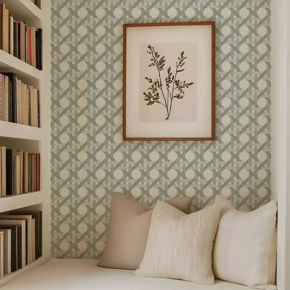 Framed botanical print on a wall with patterned wallpaper and a seating area with pillows.