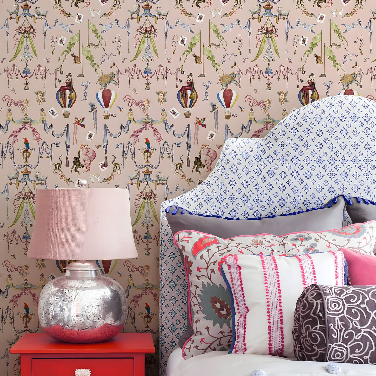 Decorative room interior with a chair, lamp, and colorful pillows against a patterned wall.