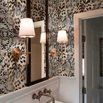 Bathroom with patterned wallpaper, mirror, and wall lights.