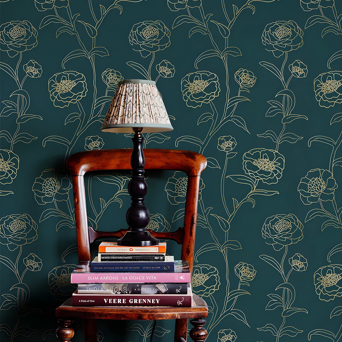 Wooden chair with a lamp and books against a floral-patterned wall.