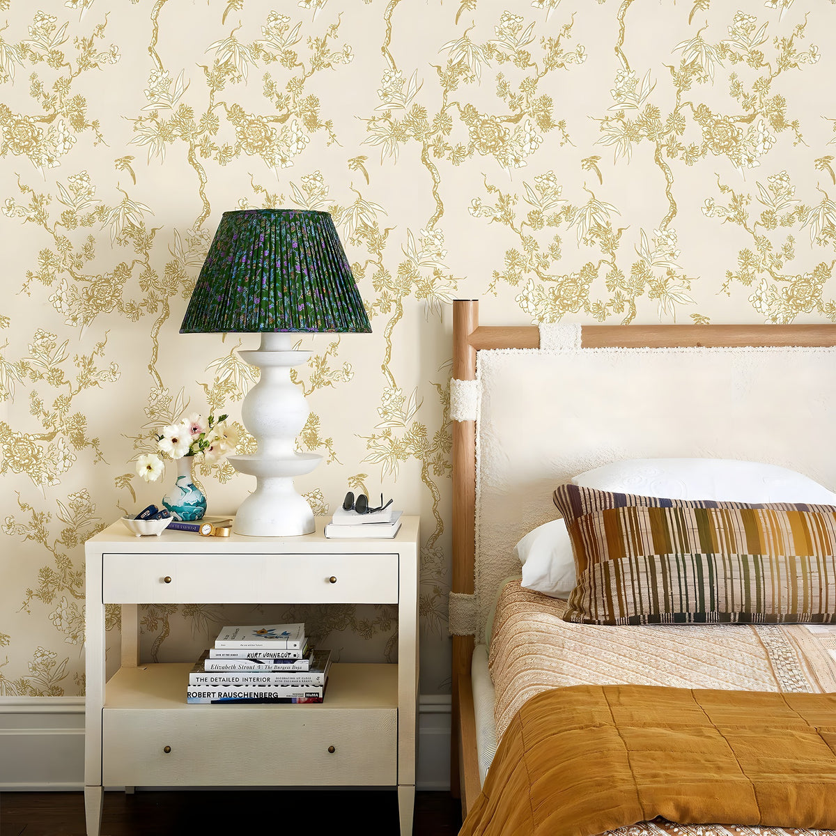 Bedroom with floral wallpaper, bed, and nightstand with lamp.