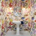 Bathroom with colorful fish and coral wallpaper and a white pedestal sink.