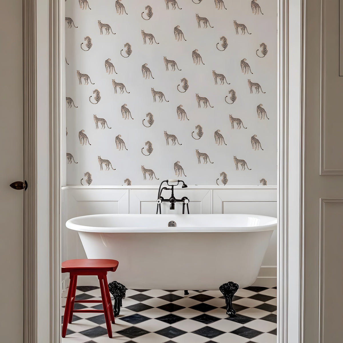 Bathroom with a freestanding bathtub, red stool, and patterned wallpaper.