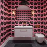 Living room with a red sofa, black coffee table, and pink walls with black cat pattern.