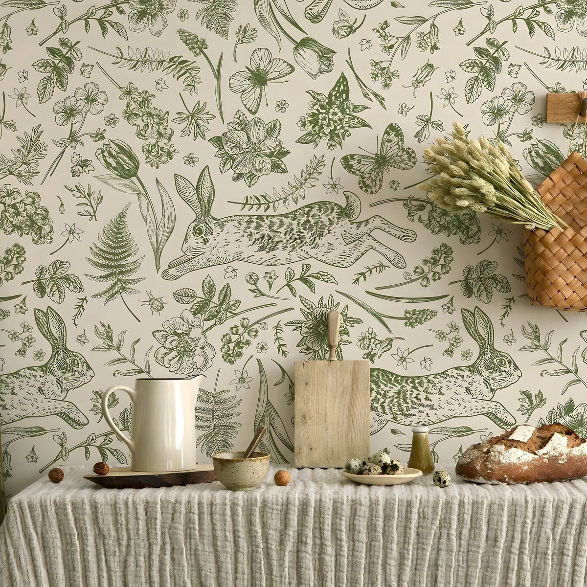 Wallpaper with green rabbits and plants on a neutral background, with a table and decorative items in the foreground.