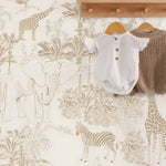 Baby clothes on hangers against a wallpaper with animal patterns