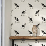 Wallpaper with a pattern of stylized figures on a neutral background, featuring a wooden shelf with a decorative item.