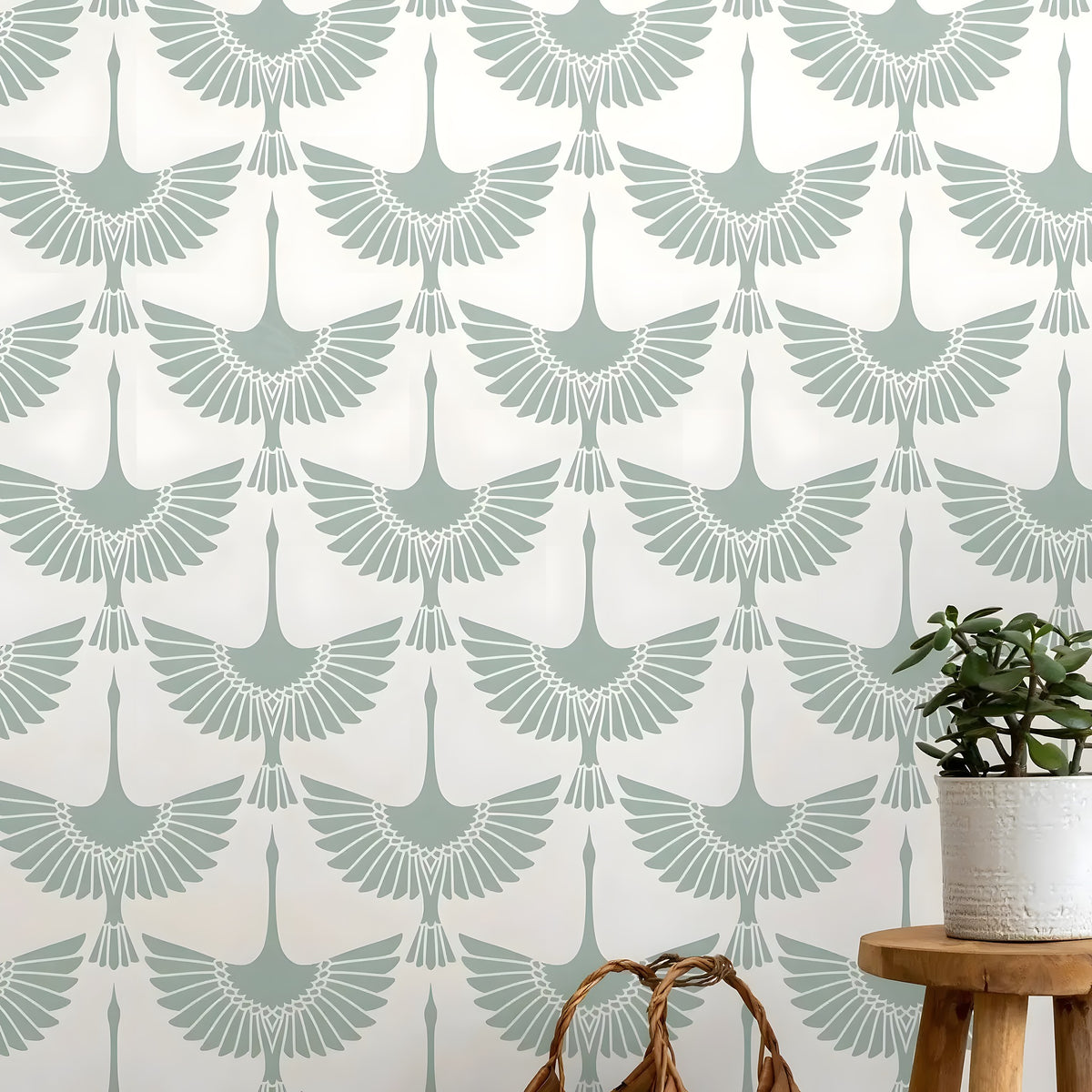 Wallpaper with crane pattern in light blue on a white background, with a plant and stool in the foreground.