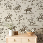 Wallpaper with cowboy and horse pattern in a room with a wooden cabinet and decor items.