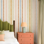 Bedroom with colorful striped wallpaper, green headboard, and pink nightstand.