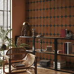Modern interior with a bookshelf, wicker chair, and decorative items against a patterned wall.