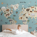 Child in bed with a world map mural featuring animals on the wall.
