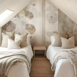 Two beds in a bedroom with decorative wall paper and pillows.