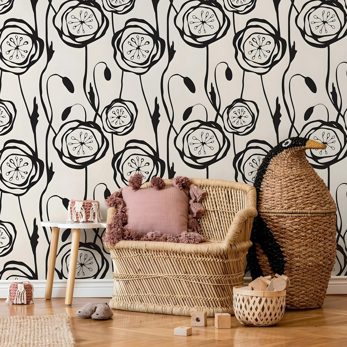 Wicker chair with pink cushion against a black and white floral wallpaper.