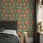 Bedroom with patterned wallpaper featuring large pink leaves on a green background.