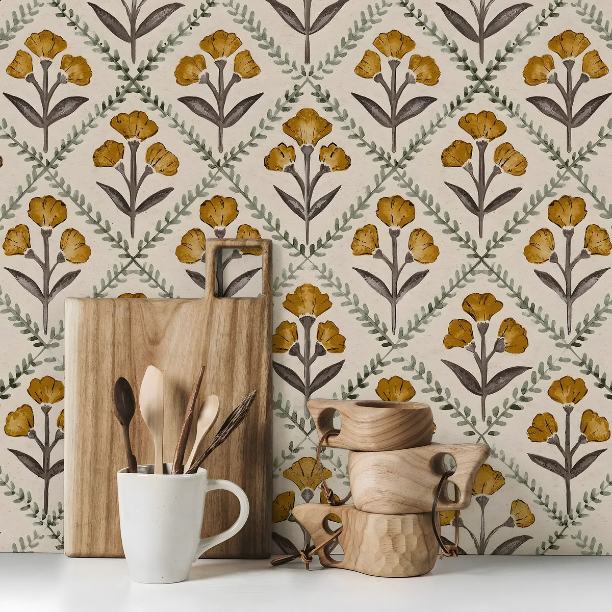 Decorative kitchen scene with wooden cutting board, mug, and decorative items against a floral wallpaper background.