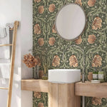 Bathroom with floral wallpaper, round mirror, and wooden vanity.