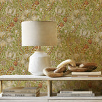 Decorative setup with a lamp and books against a floral wallpapered wall.