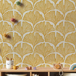 Wallpaper with a gold leaf pattern on a wall with a wooden shelf below.