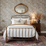Decorative bedroom with brass bed, patterned wallpaper, and wooden nightstand.