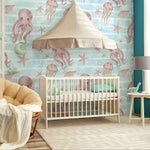 Children's room with crib, colorful wallpaper featuring sea creatures, and a lamp.