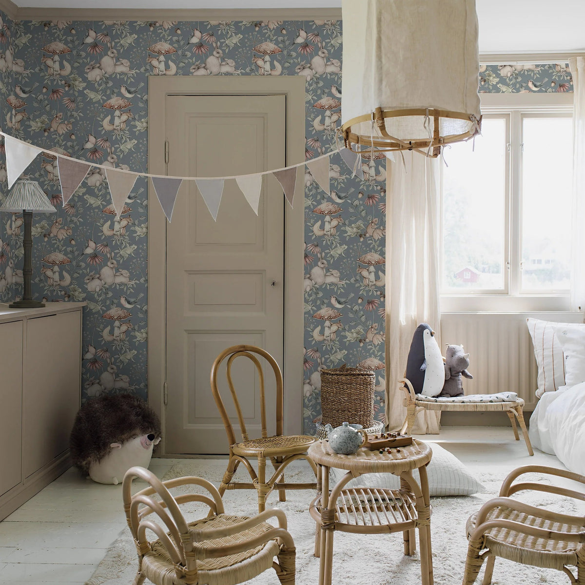 Children's room with floral wallpaper, wicker furniture, and a small table with toys.