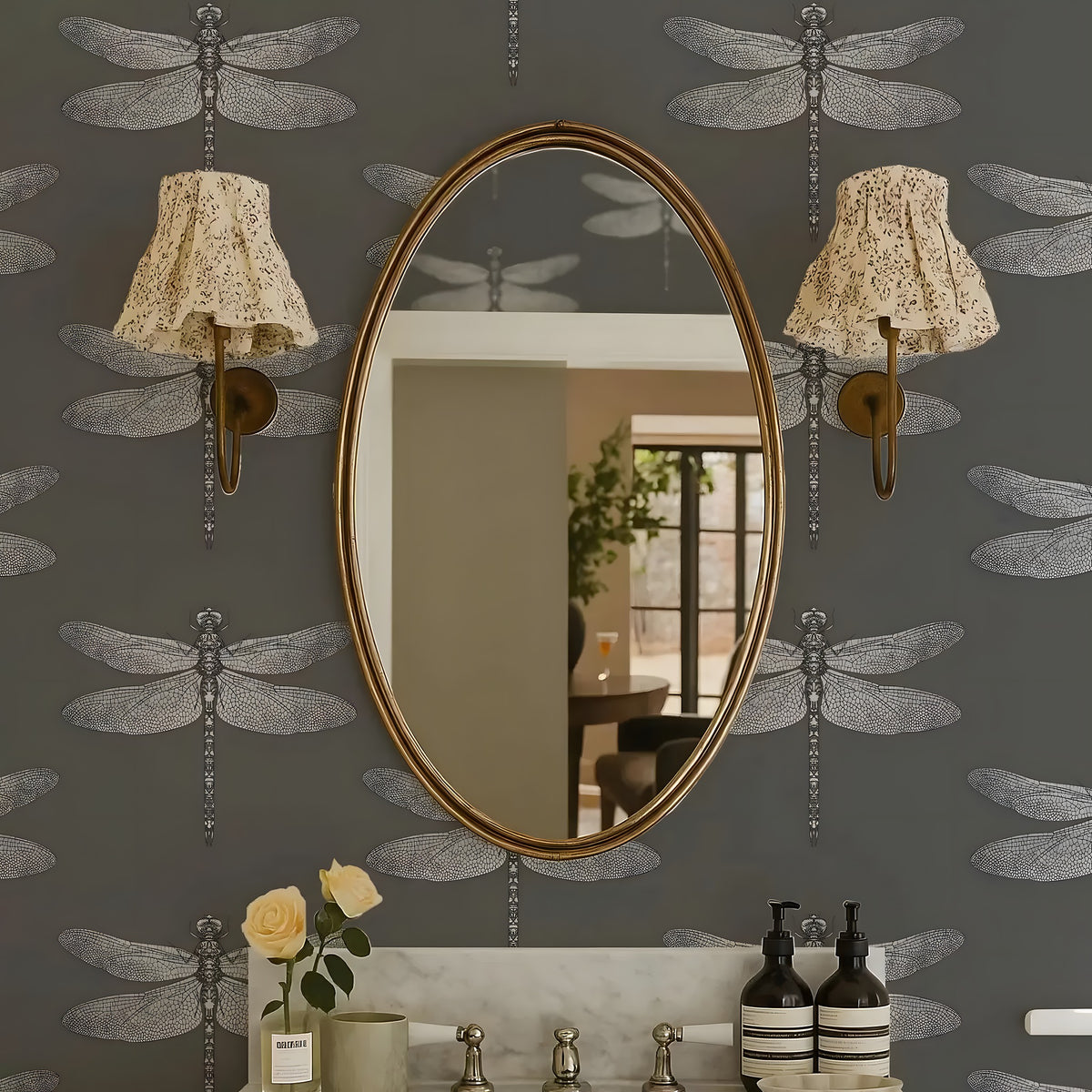 Oval mirror on a wall with dragonfly patterns and decorative lights.