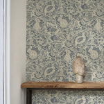 Wallpaper with nature-themed design featuring birds and foliage, wooden shelf with decorative item below.