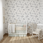 Nursery room with white crib, rocking chair, and butterfly-patterned wallpaper.