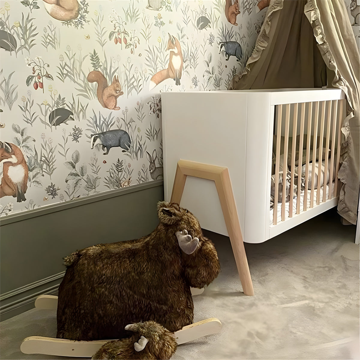 Children's room with a crib, wooden rocking horse, and forest-themed wallpaper.