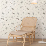 Beige wicker chair with cushion against a wall with dog-themed wallpaper