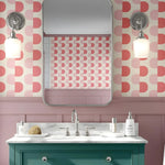 Bathroom with pink geometric wallpaper, green vanity, and white sink.