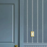 Blue wall with white leaf pattern and gold light switch