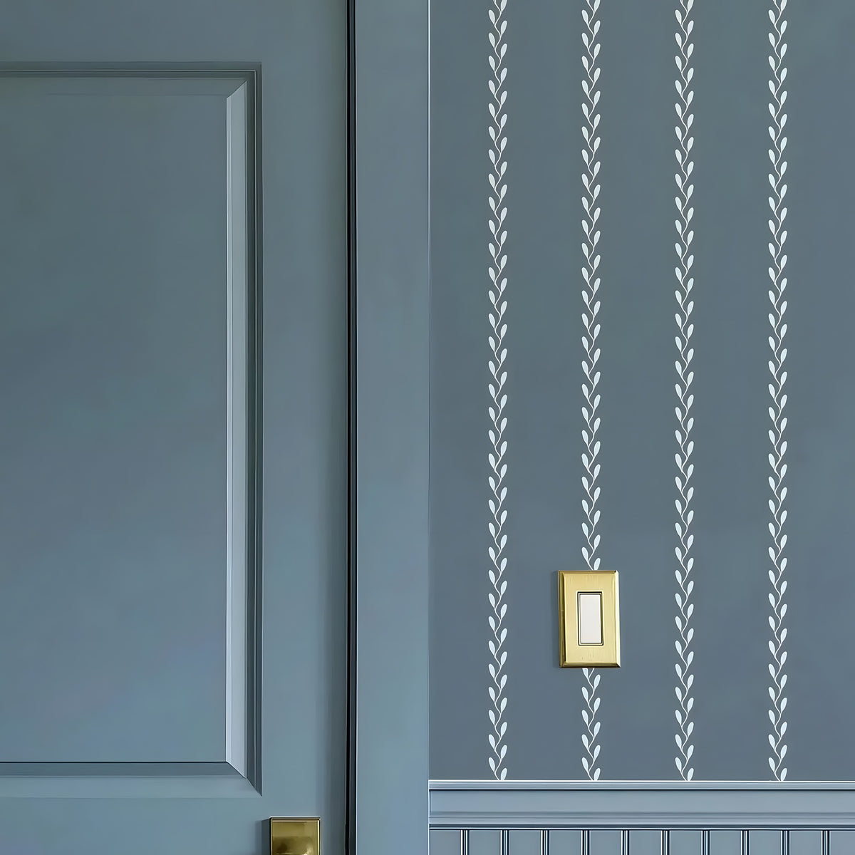 Blue wall with white leaf pattern and gold light switch