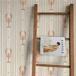 Wooden ladder with a magazine titled 'KINFOLK' against a wall with lobster patterned wallpaper.