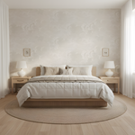Neatly made bed in a bedroom with light-colored walls and wooden flooring.
