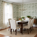 Dining room with floral wallpaper, wooden table, and white chairs.