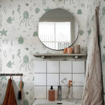 Bathroom with green underwater-themed wallpaper, round mirror, and sink.