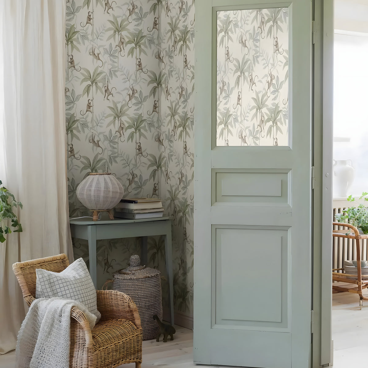 Living room with floral wallpaper, wicker chair, and open door leading to a garden.