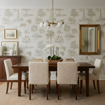 Dining room with wooden table and chairs against a wall with palm tree wallpaper.