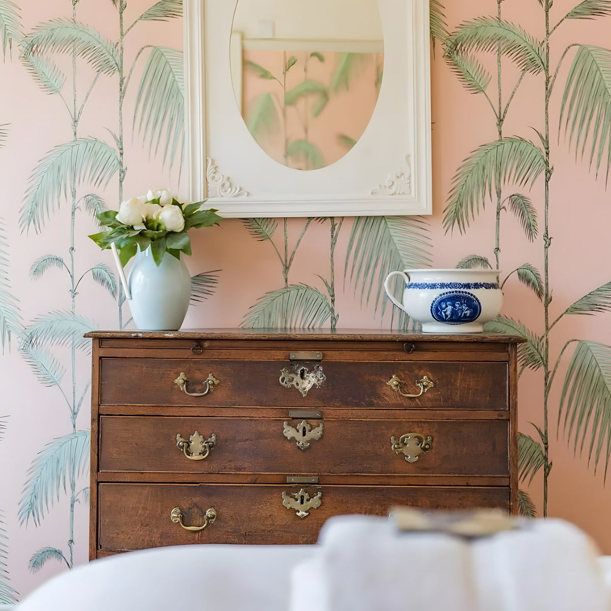 Wooden dresser with decorative items against a wall with palm leaf pattern