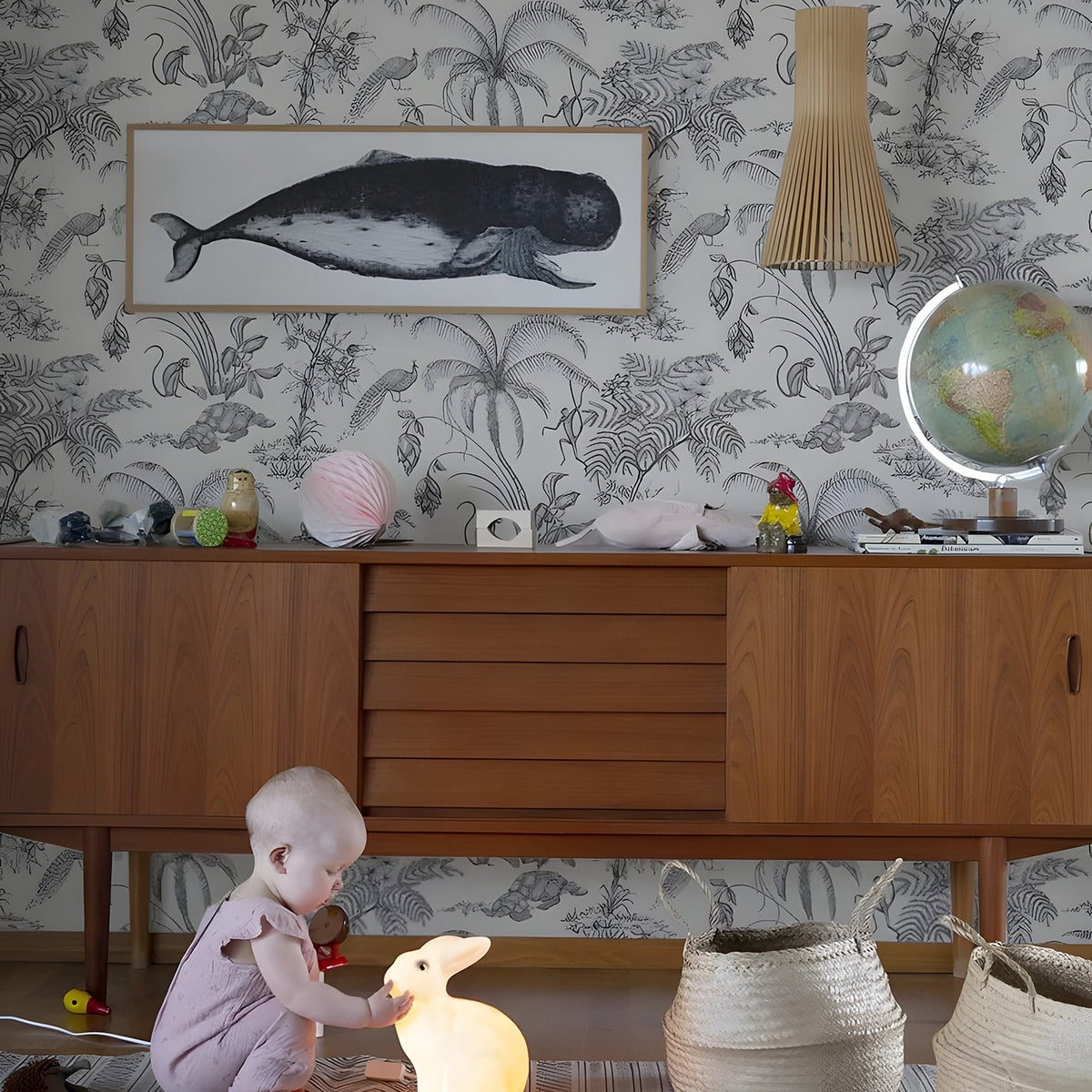 Child playing with toys on a rug in a room with wallpaper and furniture.