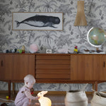 Child playing with toys on a rug in a room with wallpaper and furniture.