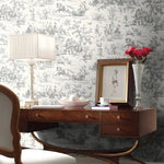 Wooden desk with decorative items against a patterned wallpaper wall.