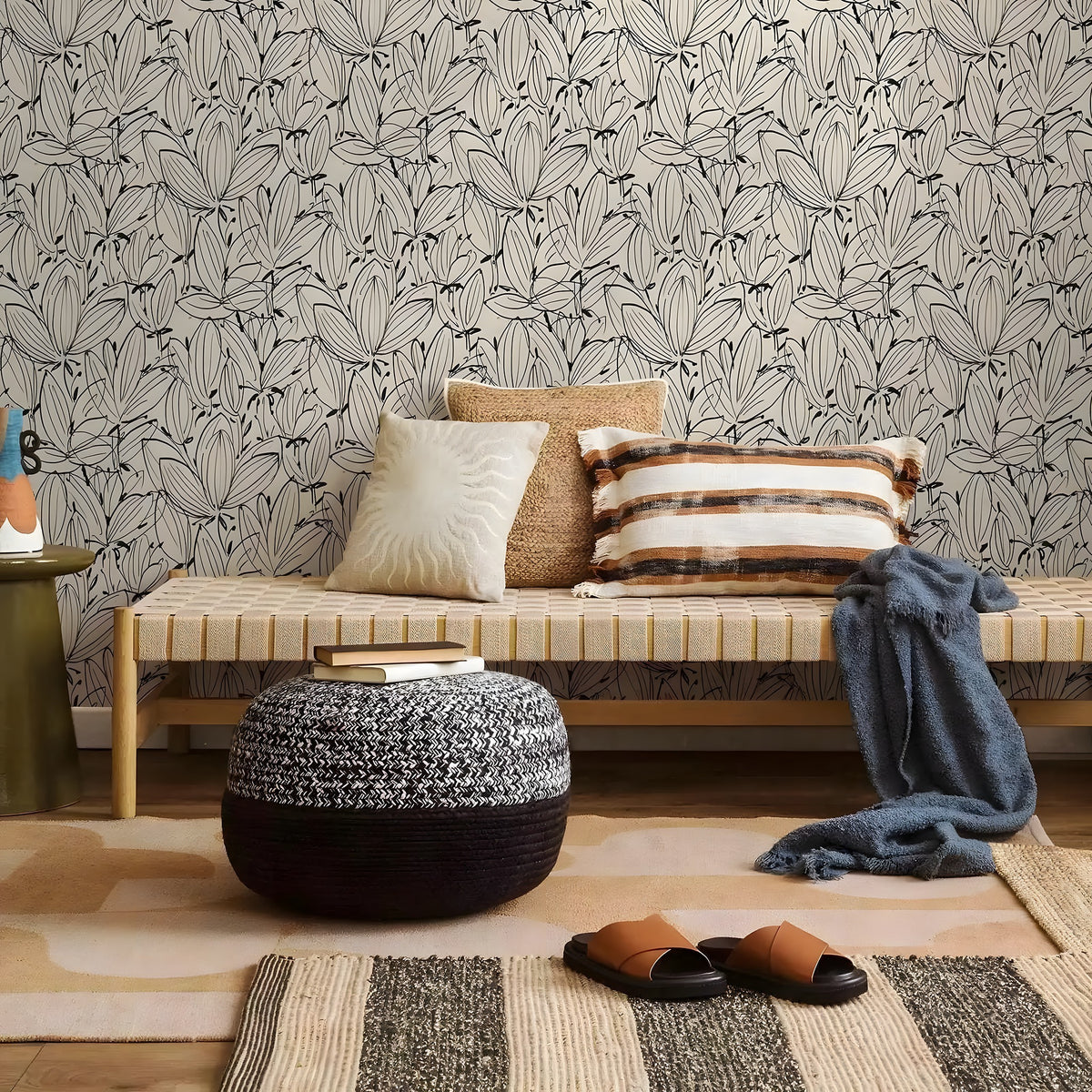Living room with a bench, ottoman, and pillows against a patterned wall.