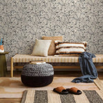 Living room with a bench, ottoman, and pillows against a patterned wall.