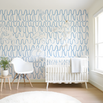 Nursery room with white crib, chair, and decorative wall pattern.