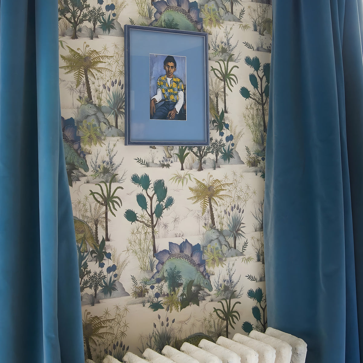Framed portrait on a wall with decorative wallpaper and blue curtains